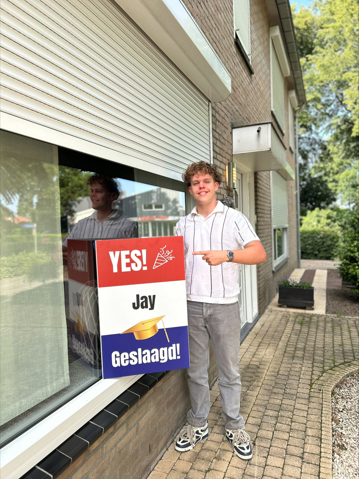 Geslaagde naast een raambord met Nederlandse vlag aan het raam